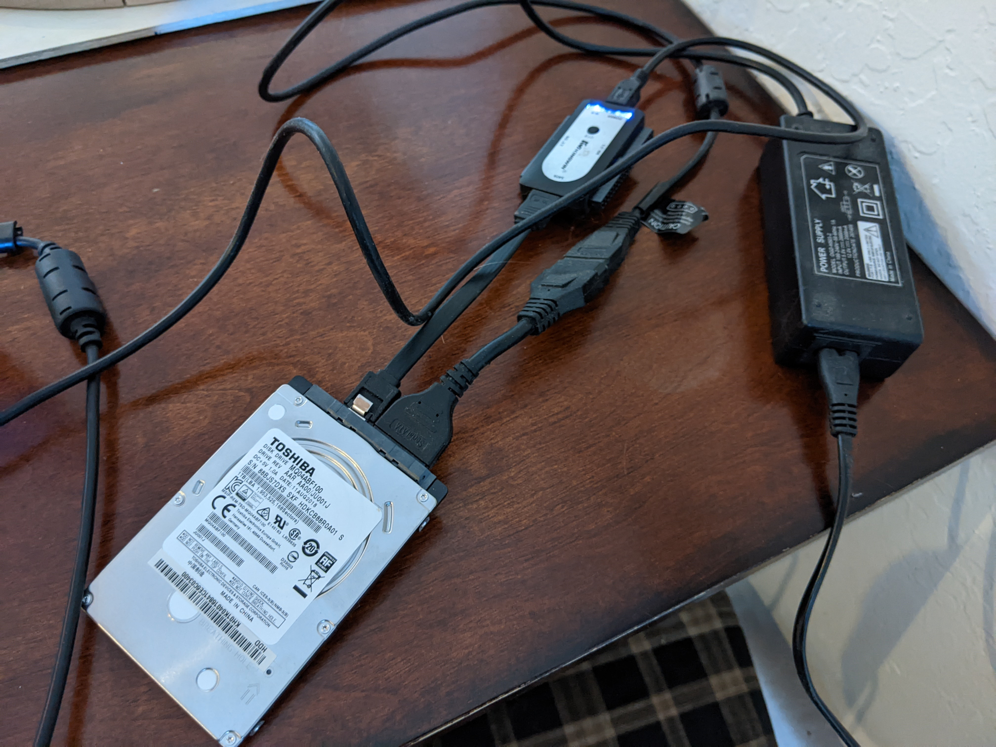 a hard drive connected to a laptop over USB with an adapter